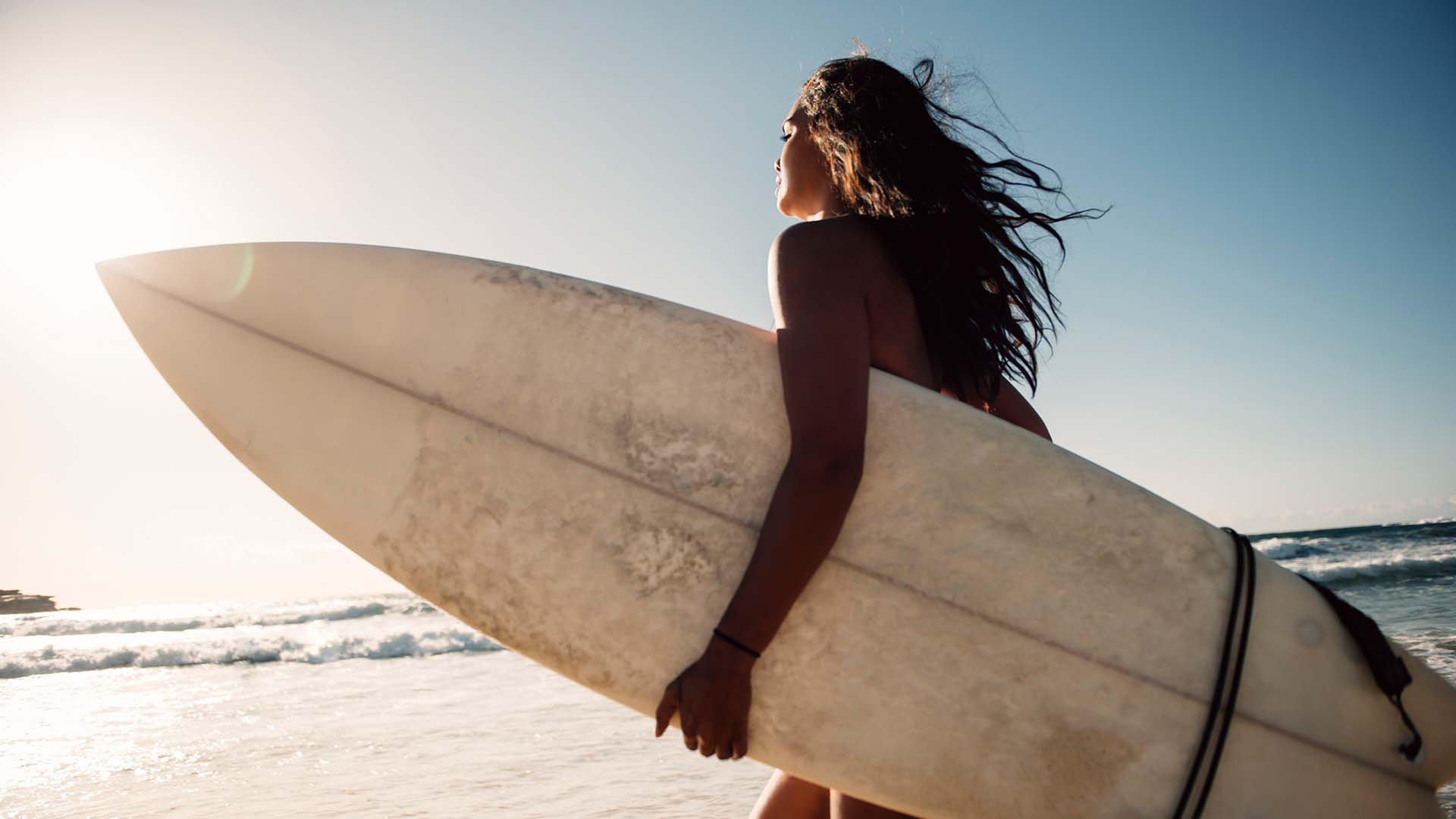 woman_with_surfboard A woman holding a surfboard at the beach
